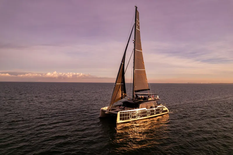 Otoctone Yacht Photos Pics 2024 Sunreef 80 sailing catamaran on calm ocean at sunset.