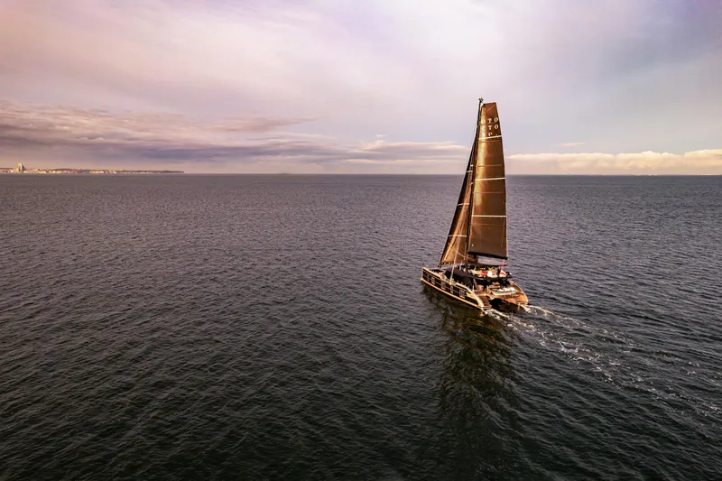 Otoctone Yacht Photos Pics 2024 Sunreef 80 sailing yacht on open sea under a dramatic sky.