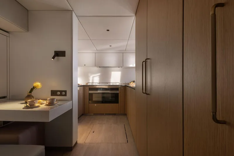 Otoctone Yacht Photos Pics Modern kitchen interior on 2024 Sunreef 80 sailing yacht, featuring sleek wood cabinetry and dining area.
