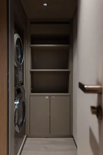 Otoctone Yacht Photos Pics Laundry area with stacked washer and dryer, shelving, and cabinets on a 2024 Sunreef 80 sailing yacht.