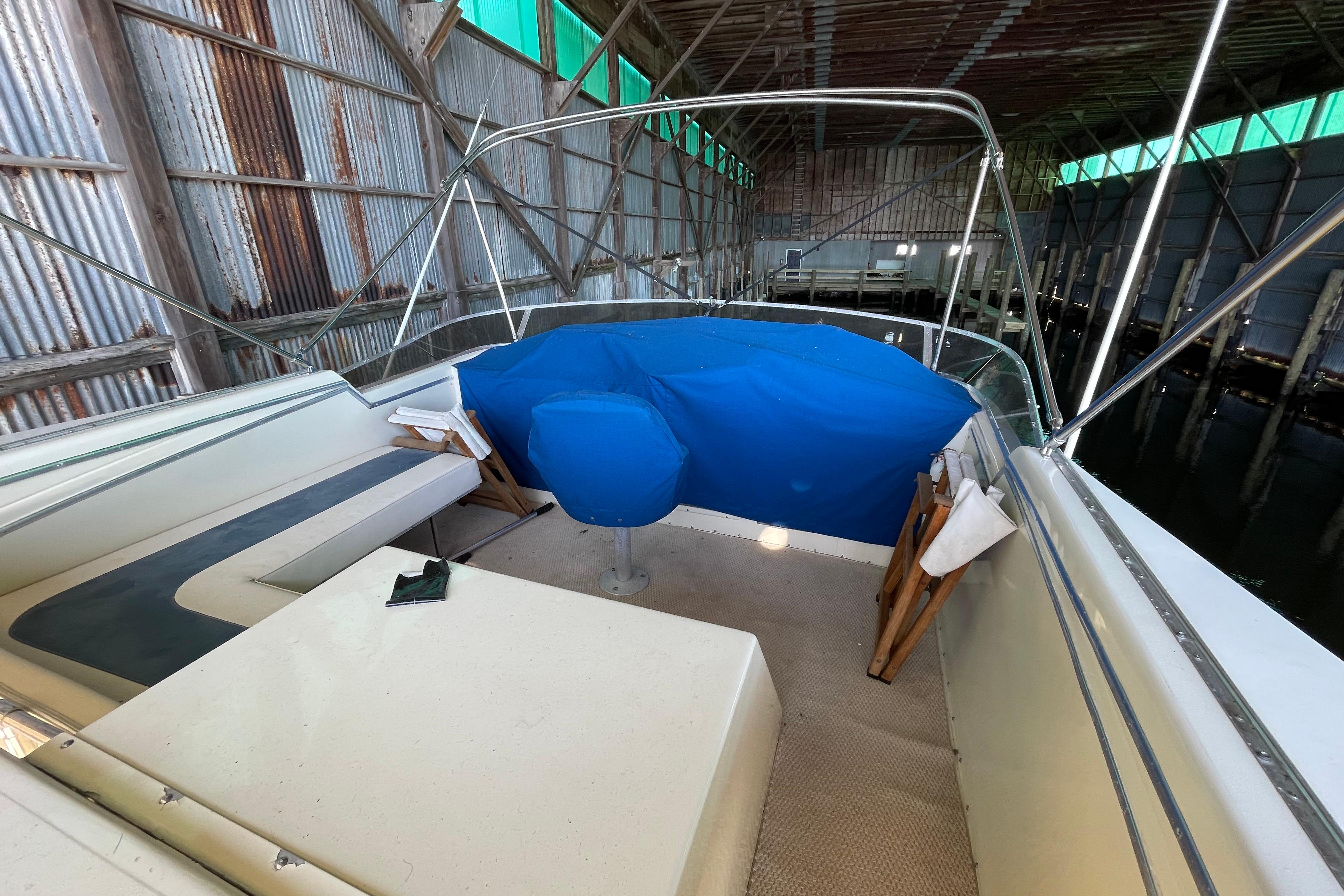 1985 Chris-Craft 426 Catalina boat interior in a covered dock, featuring seating and blue cover.