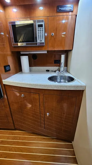  Yacht Photos Pics 2007 Regal 3760 Commodore yacht kitchenette with microwave, sink, and wooden cabinetry.