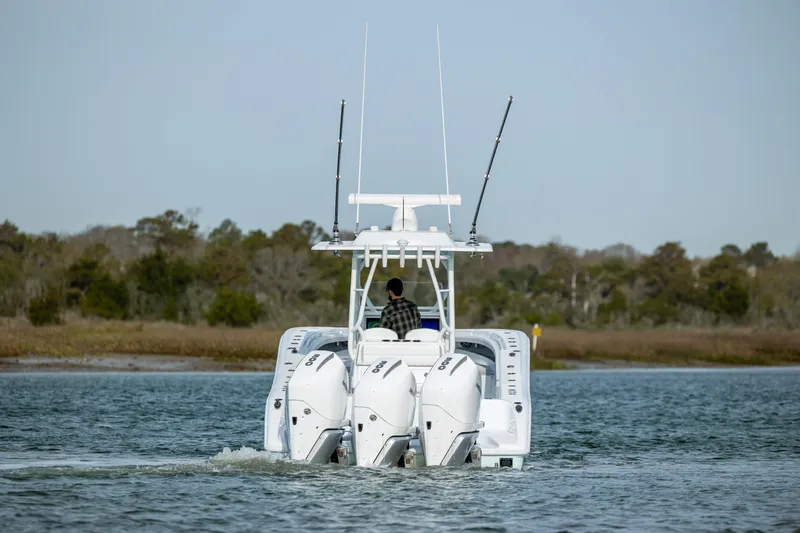  Yacht Photos Pics 2025 Yellowfin 34 Offshore boat cruising on a calm waterway, rear view.