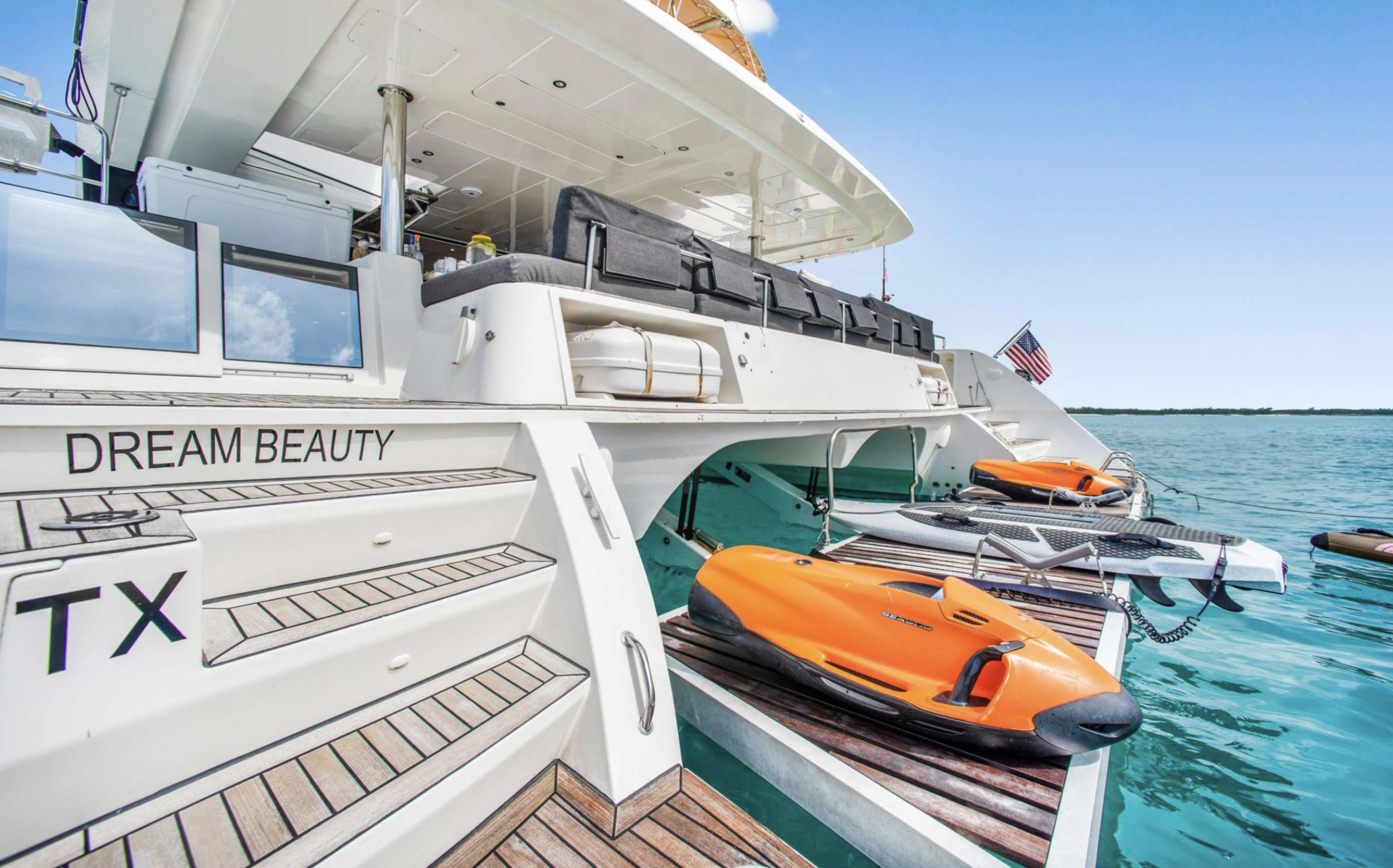 Luxury Lagoon 620 yacht with jet skis, docked on clear blue water, 2020 model.