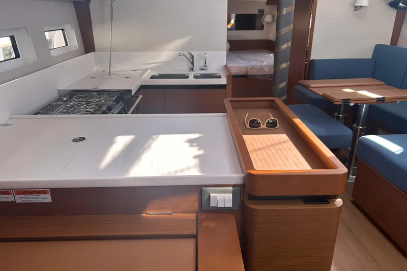 Yours To Name Yacht Photos Pics Modern interior of 2026 Jeanneau 440 Sun Odyssey yacht with kitchen and seating area.