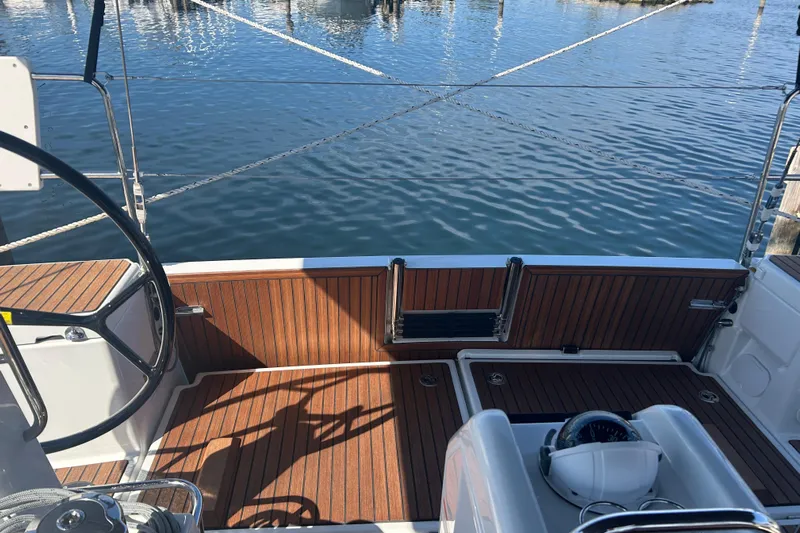 Yours To Name Yacht Photos Pics 2026 Jeanneau 440 Sun Odyssey cockpit with wooden deck, steering wheel, and marina view.