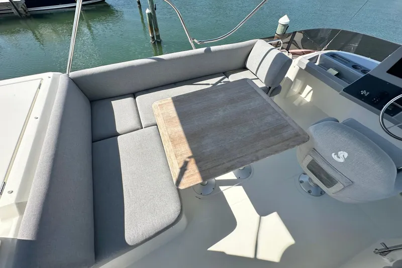 Mer Sea Yacht Photos Pics Flybridge seating area on 2021 Beneteau Swift Trawler 41 Fly, featuring gray cushions and wooden table.