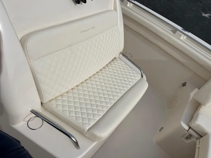  Yacht Photos Pics 2025 Grady-White Canyon 336 boat seat with quilted white upholstery and stainless steel armrests.