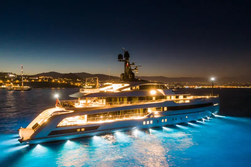 Rio Yacht Photos Pics Luxurious 2022 CRN 62m yacht illuminated at night, cruising on serene waters.