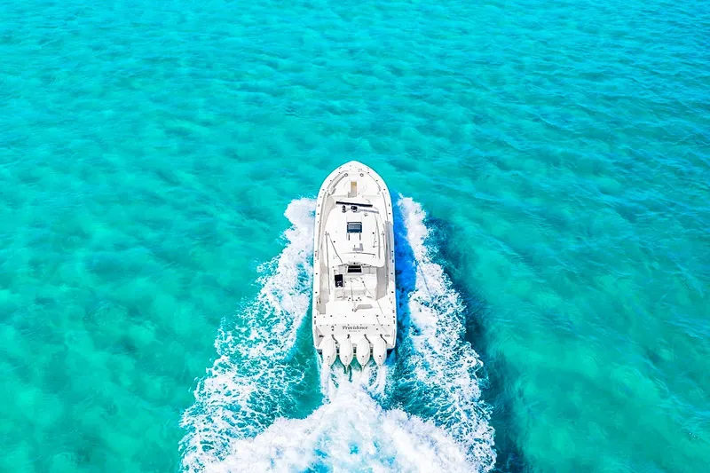  Yacht Photos Pics Aerial view of 2025 Grady-White Canyon 456 boat cruising in clear turquoise waters.