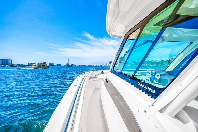  Yacht Photos Pics 2025 Grady-White Canyon 456 boat cruising on a sunny day with city skyline in background.