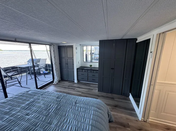  Yacht Photos Pics Bedroom interior of 1986 Stardust Cruisers houseboat with lake view, modern decor, and sliding glass doors.