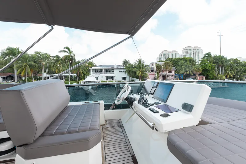 Knightlife Yacht Photos Pics Flybridge of 2017 Prestige 630 yacht with modern controls, overlooking waterfront homes and palm trees.