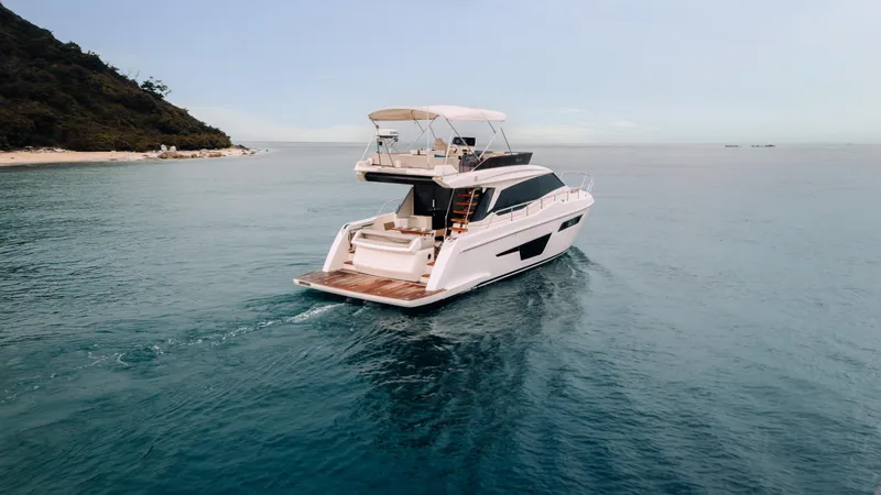  Yacht Photos Pics 2022 Ferretti Yachts 500 cruising on serene blue waters near a lush coastline.