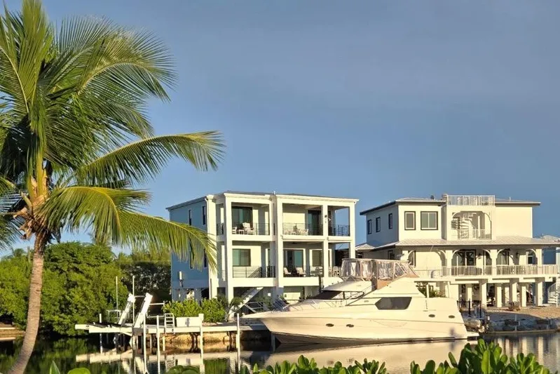 Everyday Yacht Photos Pics 2003 Silverton 453 Motor Yacht docked by modern waterfront homes, palm tree in foreground.