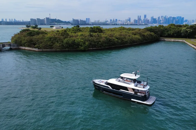  Yacht Photos Pics 2024 Azimut Magellano 60 yacht cruising near lush island and city skyline.
