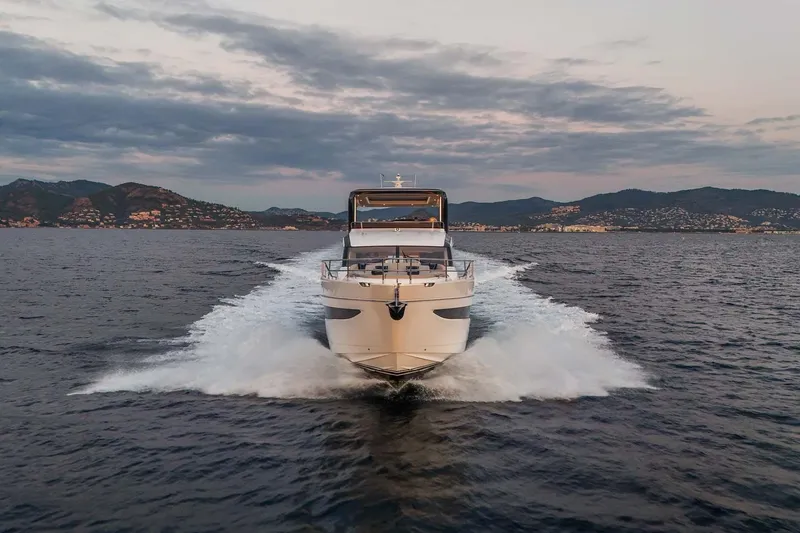  Yacht Photos Pics 2025 Princess Y72 yacht cruising on open water at sunset, with scenic mountain backdrop.