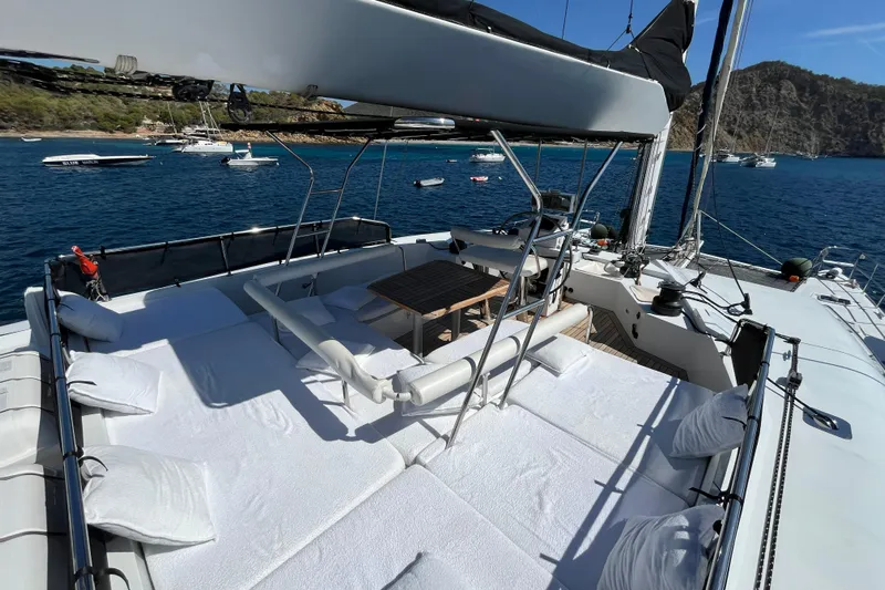 Sunreef 60 Yacht Photos Pics Luxurious Sunreef 60 yacht deck with sunbeds and dining area, anchored in a scenic bay.