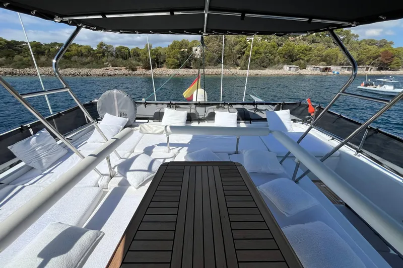 Sunreef 60 Yacht Photos Pics Luxurious Sunreef 60 yacht deck with cushioned seating, wooden table, and scenic ocean view.