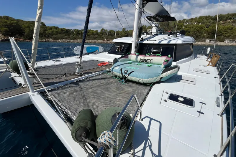 Sunreef 60 Yacht Photos Pics Sunreef 60 yacht deck with inflatable water toy, anchored near a scenic coastline.