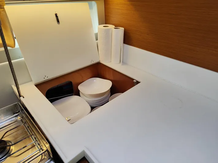 Aurora Yacht Photos Pics Galley storage in 2018 Jeanneau Sun Odyssey 490 yacht with dishes and paper towels.