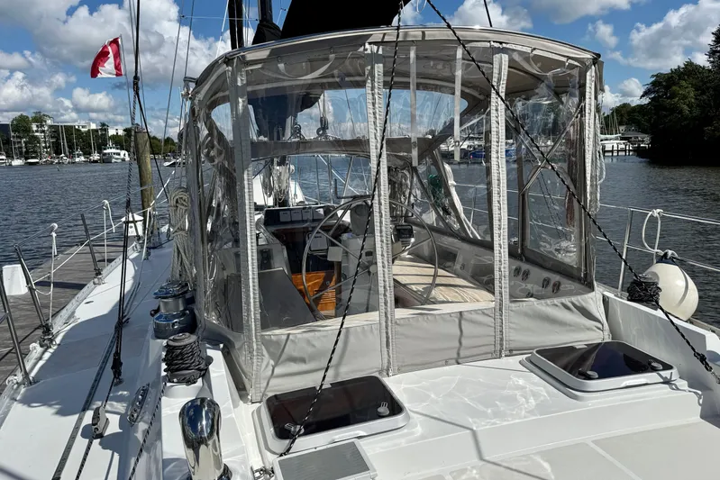 Su Ching Yacht Photos Pics 1984 Tayana 55 sailboat with enclosed cockpit, docked by a scenic waterfront.
