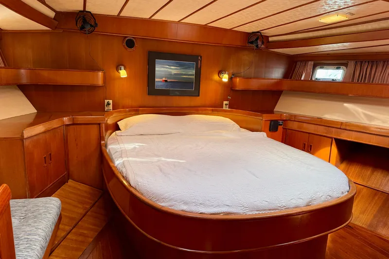 Su Ching Yacht Photos Pics Luxurious wooden cabin interior of 1984 Tayana 55 yacht with cozy bed and ambient lighting.