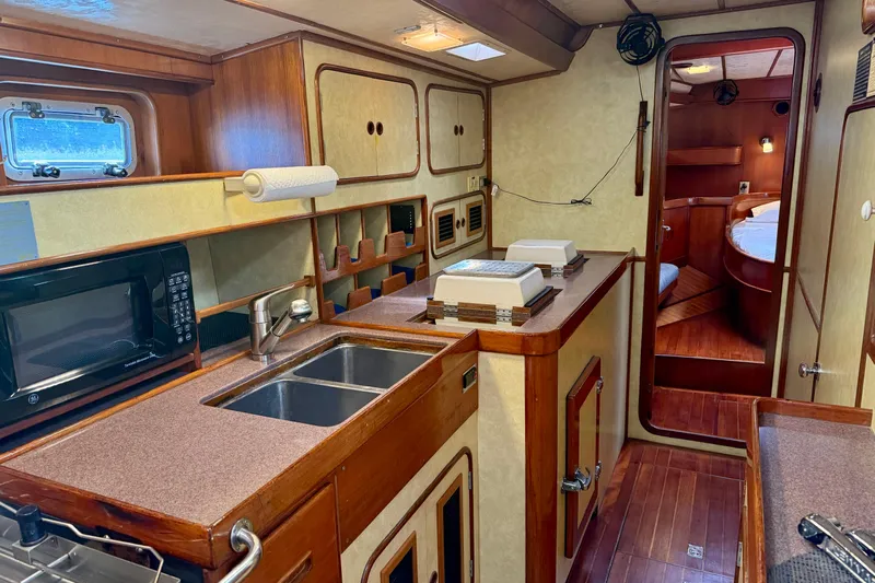 Su Ching Yacht Photos Pics Interior of 1984 Tayana 55 yacht featuring a cozy kitchen and wooden cabinetry.