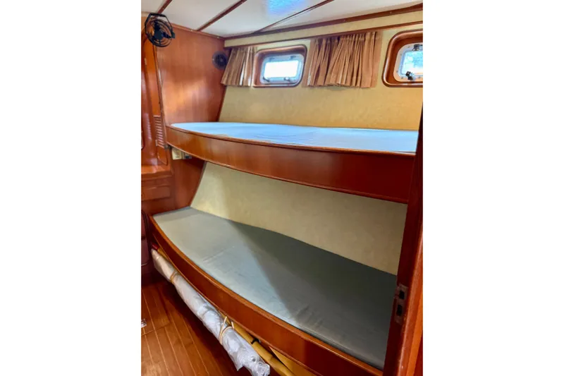 Su Ching Yacht Photos Pics Interior of 1984 Tayana 55 sailboat featuring wooden bunk beds and porthole windows.