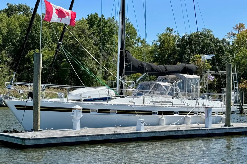 Su Ching Yacht Photos Pics Sailboat docked with Canadian flag, Tayana 55, 1984 model, surrounded by lush greenery.