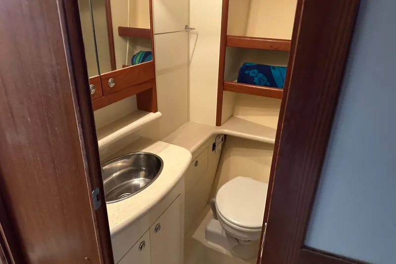 Mischievous Mermaid Yacht Photos Pics Compact bathroom in 2004 Hunter Deck Salon yacht with sink, toilet, and storage shelves.