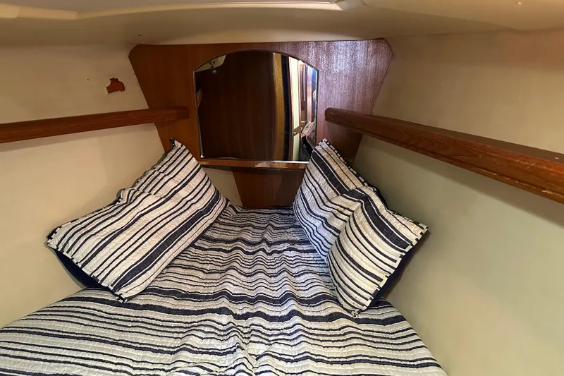 Mischievous Mermaid Yacht Photos Pics Cozy cabin interior of 2004 Hunter Deck Salon with striped bedding and wooden accents.
