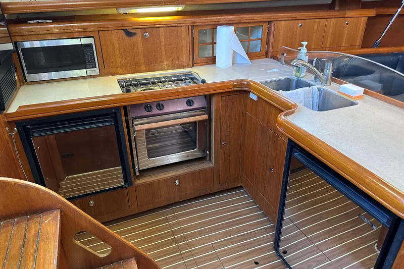 Mischievous Mermaid Yacht Photos Pics 2004 Hunter Deck Salon yacht kitchen with wood cabinetry, stove, oven, microwave, and sink.