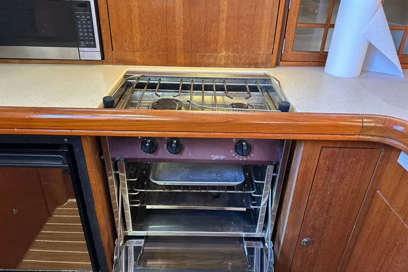 Mischievous Mermaid Yacht Photos Pics 2004 Hunter Deck Salon kitchen with stove, oven, and microwave in wooden cabinetry.