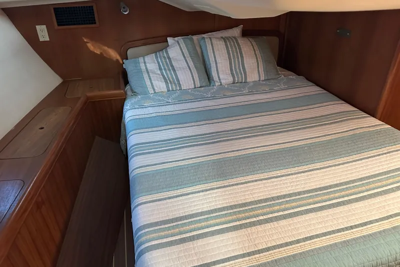 Mischievous Mermaid Yacht Photos Pics Cozy cabin interior of 2004 Hunter Deck Salon with striped bedding and wooden accents.