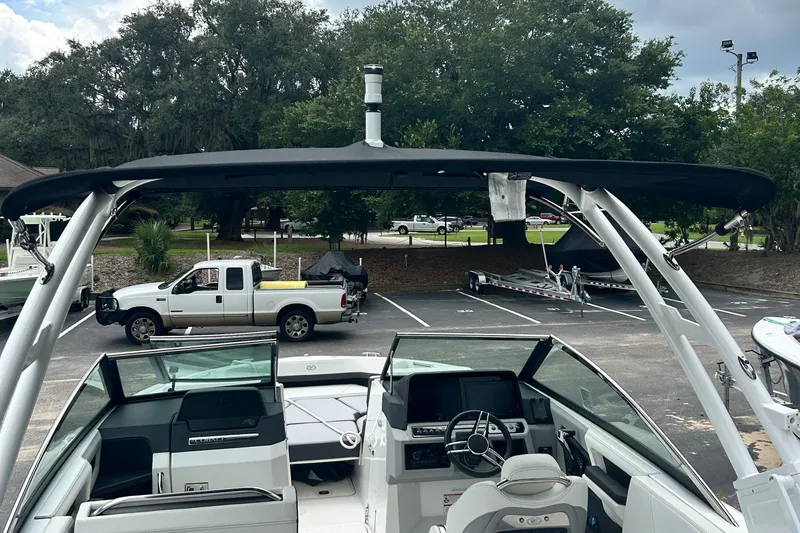  Yacht Photos Pics 2024 Cobalt R6 boat interior with steering wheel, parked truck, and trees in the background.
