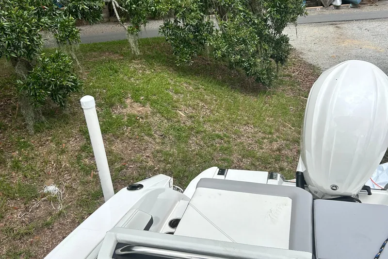  Yacht Photos Pics 2024 Cobalt R6 boat with outboard motor, parked on grassy area near trees.