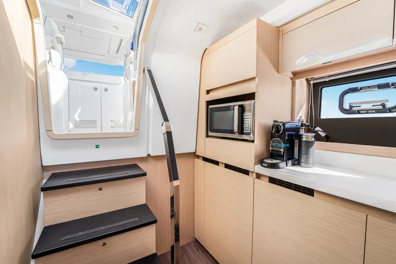 Equanimity Yacht Photos Pics Modern interior of 2023 Jeanneau DB43 yacht with kitchenette and stairs.