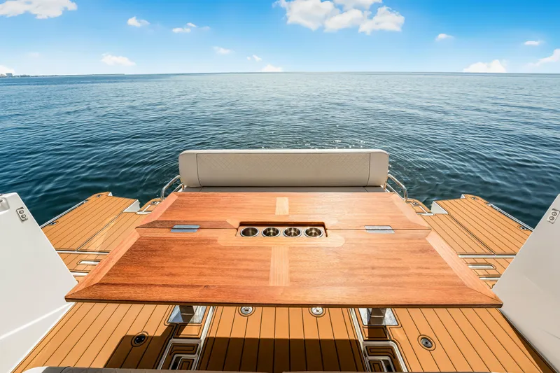 Equanimity Yacht Photos Pics 2023 Jeanneau DB43 yacht deck with wooden table, overlooking calm ocean waters.