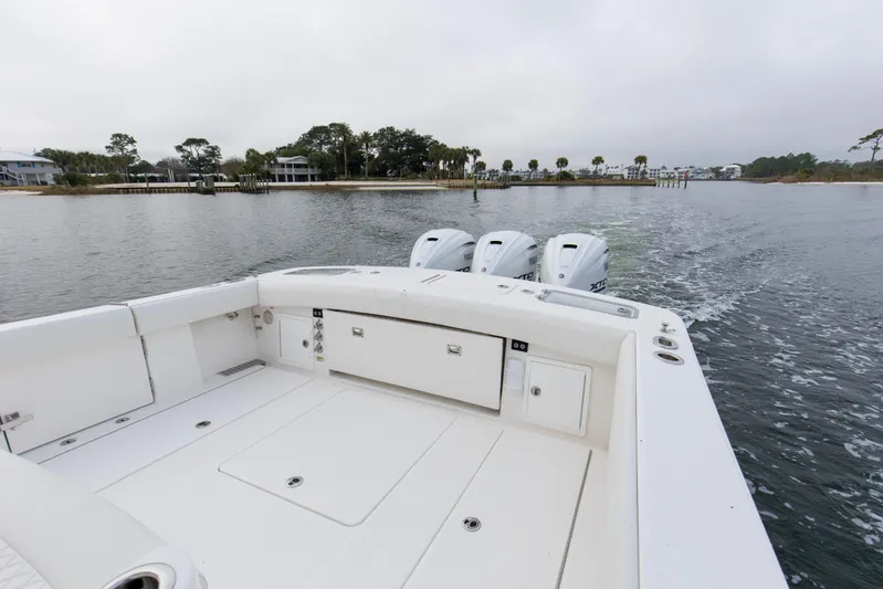  Yacht Photos Pics 2024 Regulator 37 boat with triple outboard engines cruising on a calm waterway.