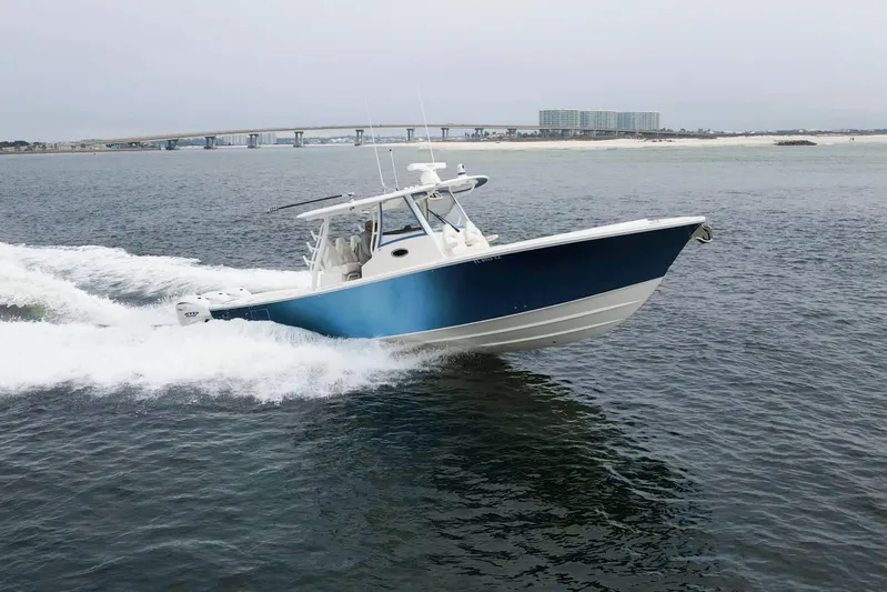  Yacht Photos Pics 2024 Regulator 37 boat cruising on open water near a coastal bridge.