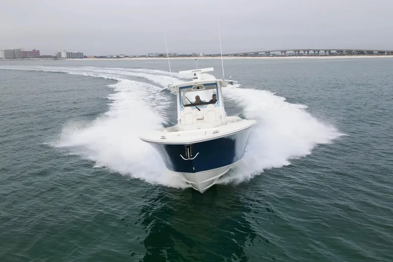  Yacht Photos Pics 2024 Regulator 37 boat cruising on open water with cityscape in background.