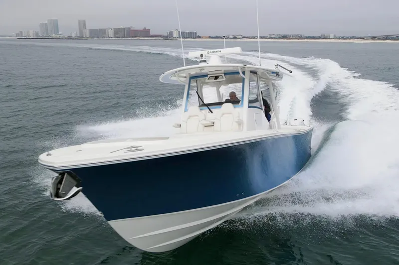  Yacht Photos Pics 2024 Regulator 37 boat cruising on open water with city skyline in background.