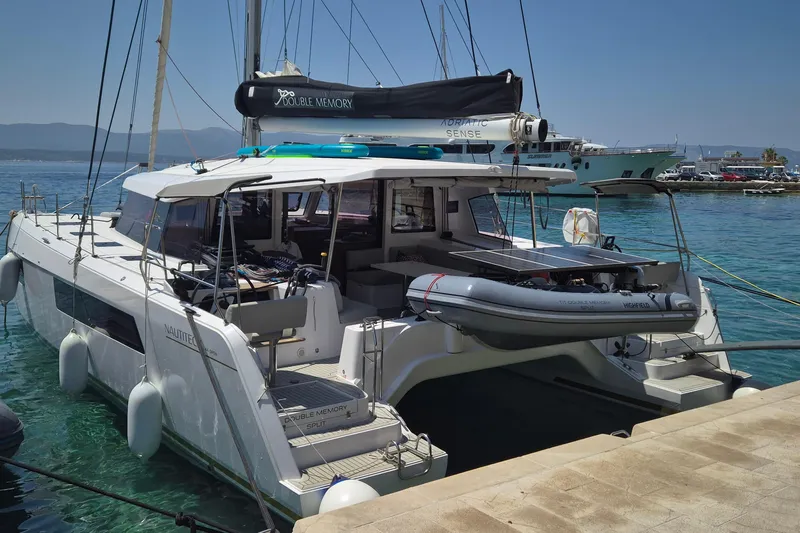 Double Memory Yacht Photos Pics 2023 Nautitech 44 catamaran docked at a marina, featuring a sleek design and inflatable dinghy.