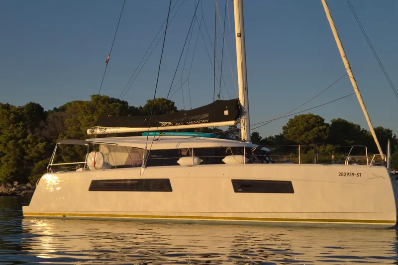 Double Memory Yacht Photos Pics 2023 Nautitech 44 catamaran anchored in calm waters at sunset.