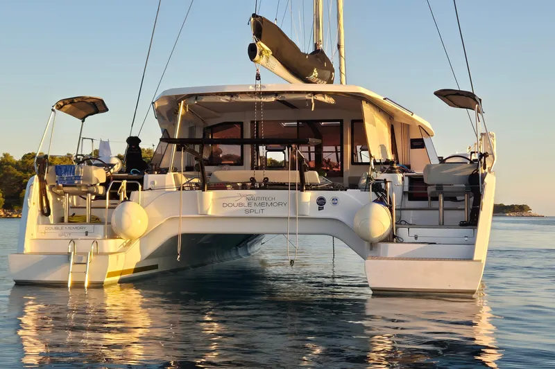 Double Memory Yacht Photos Pics 2023 Nautitech 44 catamaran on calm water at sunset.