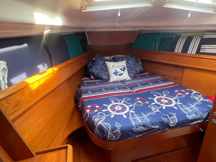 Karisma Yacht Photos Pics Cozy cabin interior of 2006 Jeanneau Sun Odyssey 45 with nautical-themed bedding.