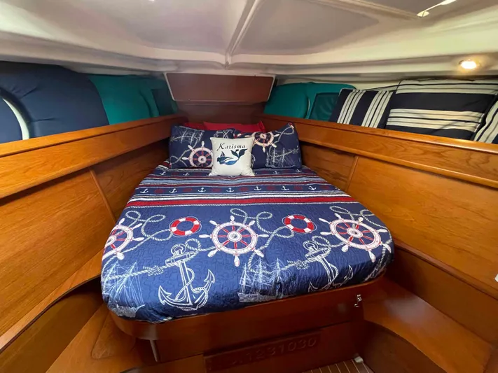 Karisma Yacht Photos Pics Cozy cabin interior of 2006 Jeanneau Sun Odyssey 45 with nautical-themed bedding.