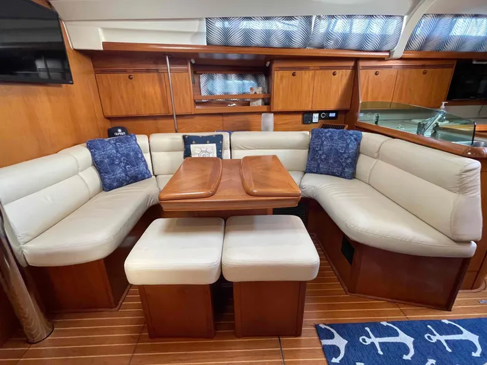 Karisma Yacht Photos Pics Interior of 2006 Jeanneau Sun Odyssey 45 yacht with cozy seating and wooden table.