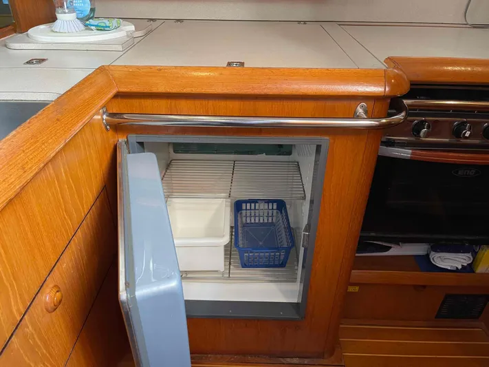 Karisma Yacht Photos Pics 2006 Jeanneau Sun Odyssey 45 yacht kitchen with open fridge and wooden cabinetry.